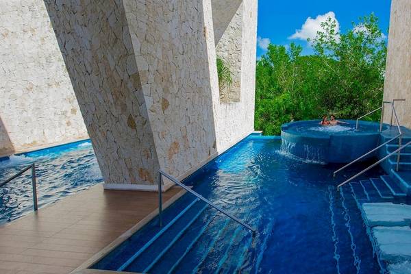 Ein blauer Pool mit Wasserfall und Liegen im Grand Sirenis Riviera Maya Resort.