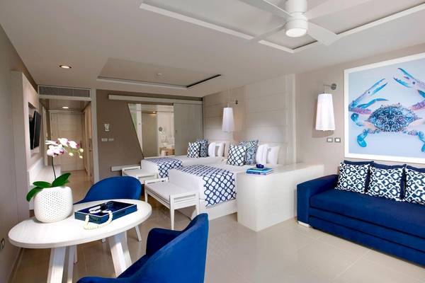 Innenansicht einer Suite im Grand Sirenis Riviera Maya Resort mit blauen Möbeln und einem großen Bild von einem Krebs.