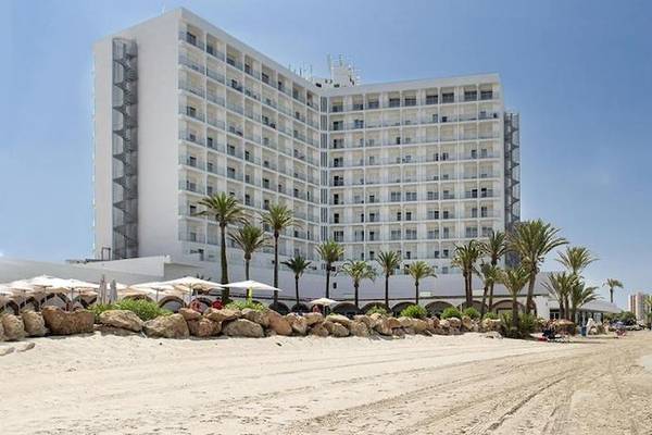 Außenansicht des Roc Barlovento Hotels am Strand mit vielen Palmen und einem blauen Himmel.