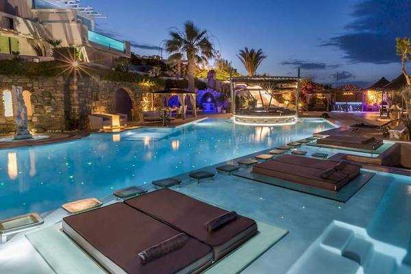 Der Pool des Kivotos Mykonos Hotels bei Nacht mit Lounge-Liegestühlen und beleuchteten Wasserflächen.