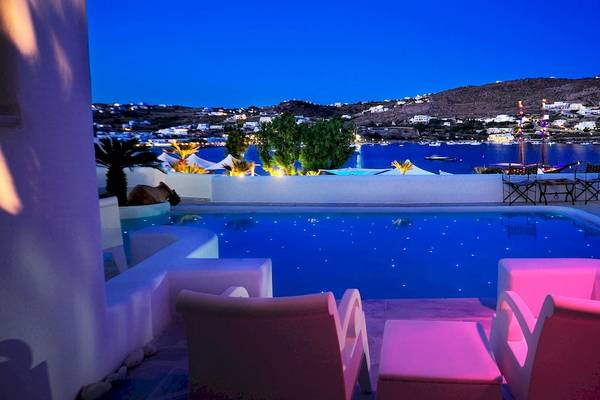 Nachtansicht des Pools im Kivotos Mykonos Hotel mit blauem Wasser und pinken Leuchten.