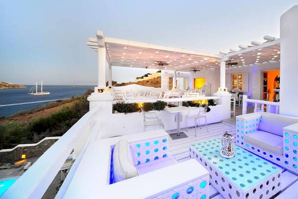 Kivotos Mykonos Terrasse mit Blick auf das Meer und eine Segelyacht im Hintergrund.