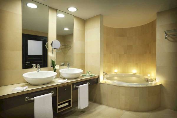 Badezimmer im Roca Nivaria Gran Hotel mit zwei Waschbecken, Spiegel und Badewanne mit Kerzen.