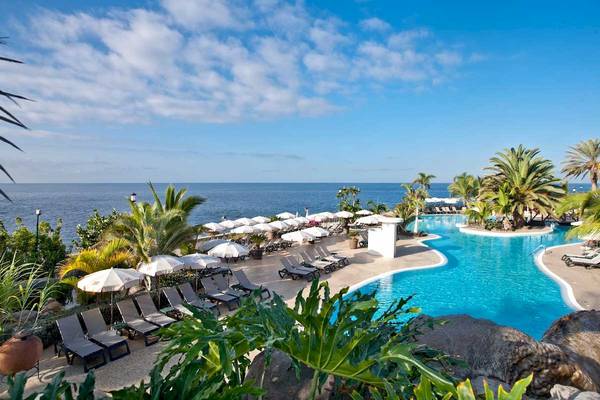 Außenbereich des Pools im Roca Nivaria Gran Hotel mit Lounge-Stühlen und Sonnenschirmen.