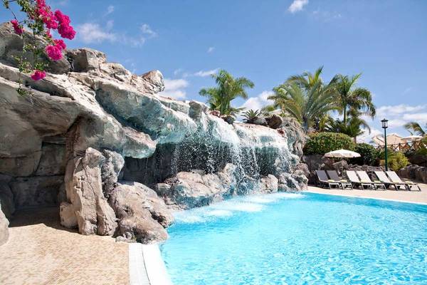 Außenpool mit Wasserfall im Roca Nivaria Gran Hotel mit Liegestühlen und Sonnenschirmen.