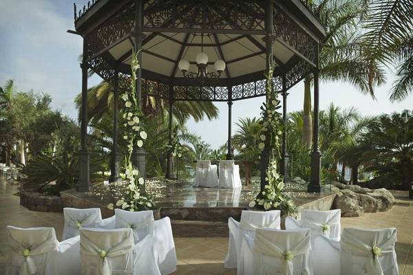 Hochzeitszeremonie im Garten des Roca Nivaria Gran Hotel, umgeben von weißen Stühlen und Blumen.