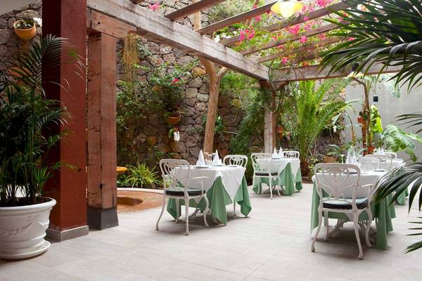 Gartenrestaurant im Roca Nivaria Gran Hotel mit grünen Tischen und weißen Stühlen.