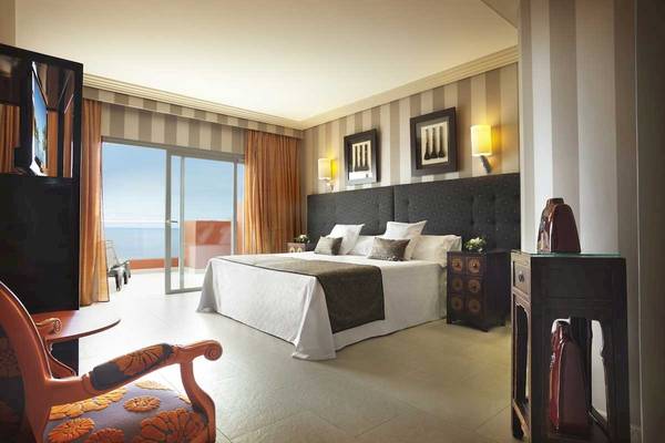 Schlafzimmer im Roca Nivaria Gran Hotel mit einem großen Bett, einer Aussicht auf das Meer und einer stilvollen Einrichtung.