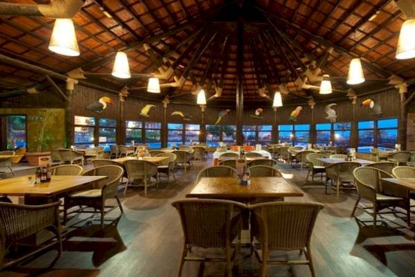 Innenbereich des Restaurants im Elba Sara Beach & Golf Resort mit Holzmöbeln und großen Fenstern.