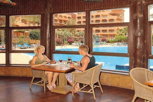 Zwei Personen sitzen am Tisch und essen im Elba Sara Beach & Golf Resort mit Blick auf den Pool.