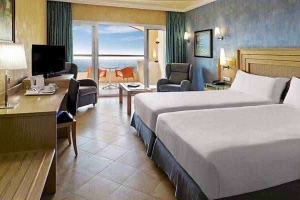 Hotelzimmer mit Meerblick im Elba Sara Beach & Golf Resort mit zwei Betten, Fernseher und Tisch.