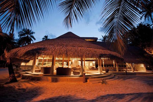 Die Kuramathi Maldives Hotel-Nachtansicht mit beleuchteten Gebäuden und Palmen.