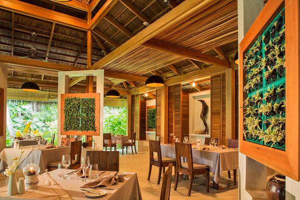 Innenbereich des Kuramathi Maldives Hotel mit Esstischen und hängenden Lampen.