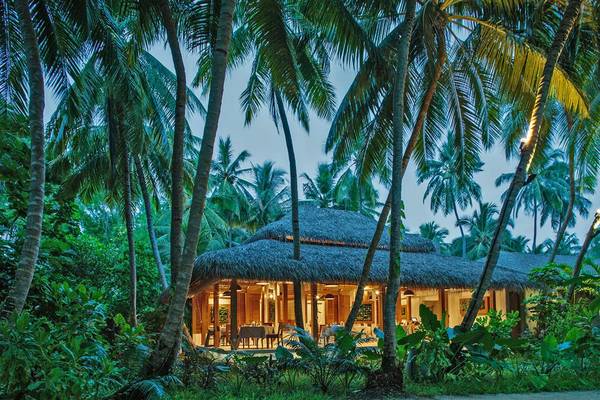 Nachtansicht des Kuramathi Maldives Hotels, umgeben von Palmen und Beleuchtung.