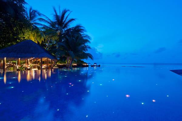 Nachtansicht des beleuchteten Infinity-Pools im Kuramathi Maldives