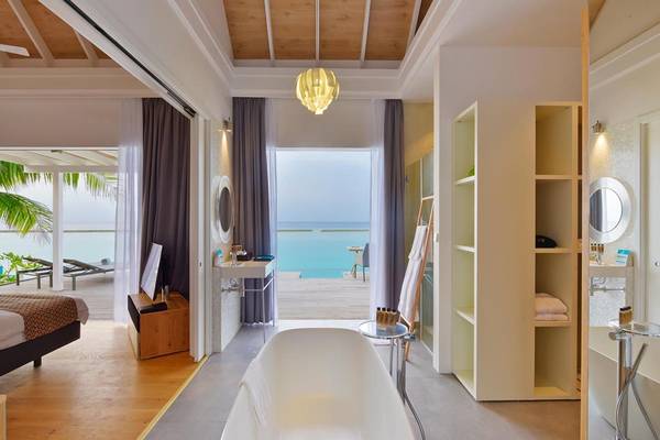 Innenansicht eines Hotelzimmers im Kuramathi Maldives mit Badewanne, offenem Fenster und Meerblick.