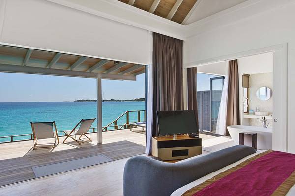 Innenansicht eines Schlafzimmers im Kuramathi Maldives mit Blick auf das Meer, Balkon und moderner Einrichtung.