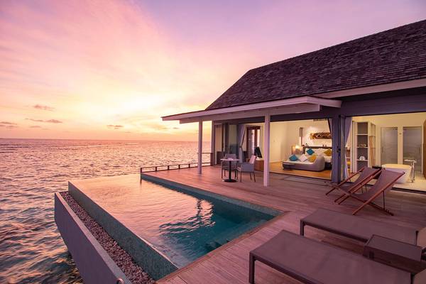 Wasservilla des Kuramathi Maldives Hotels bei Sonnenuntergang mit Blick auf den Ozean.
