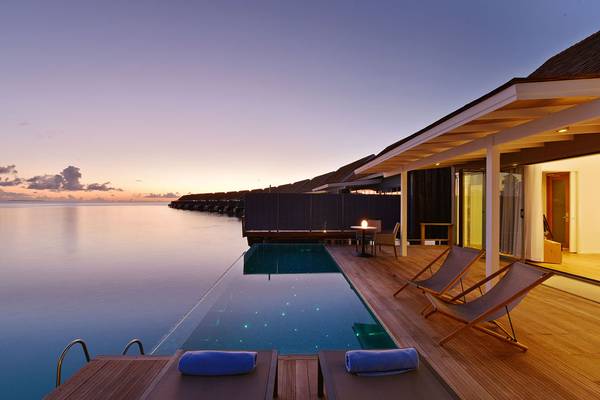 Pooldeck des Kuramathi Maldives Hotels bei Sonnenuntergang mit Blick auf das Meer