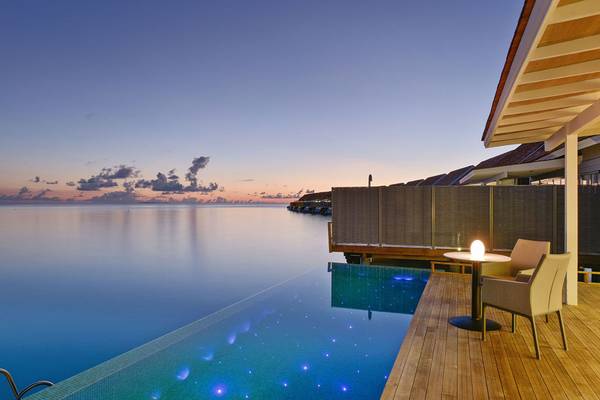 Pool mit beleuchtetem Wasser und Sitzbereich am Abend im Kuramathi Maldives