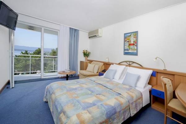 Ein modernes Hotelzimmer im BlueSun Hotel Borak mit Blick auf die Berge und einem großen Bett.