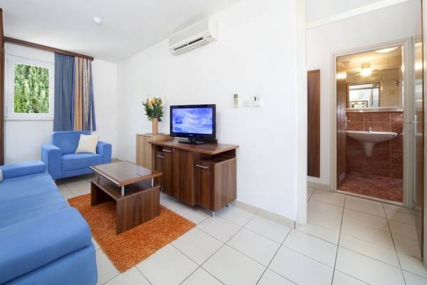 Das Wohnzimmer des BlueSun Hotel Borak mit blauen Sofas, einem Fernseher und einem Couchtisch.