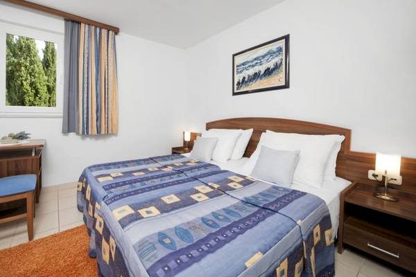 Innenansicht eines Schlafzimmers im BlueSun Hotel Borak mit zwei Betten, Tisch, Stuhl und Fenster.