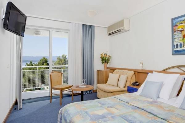 Zimmer im BlueSun Hotel Borak mit einem Bett, Möbeln und einem Blick auf den Garten.