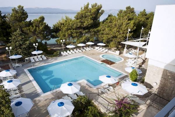 Luftaufnahme des Poolbereichs des BlueSun Hotel Borak mit weißen Sonnenschirmen und Liegestühlen.