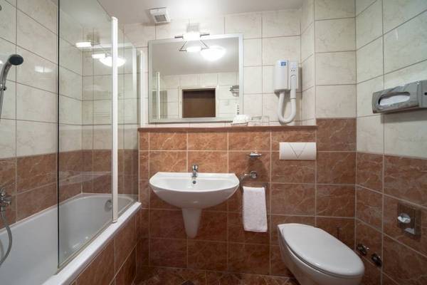 Badezimmer im BlueSun Hotel Borak mit Badewanne, Waschbecken, Toilette und Spiegel.