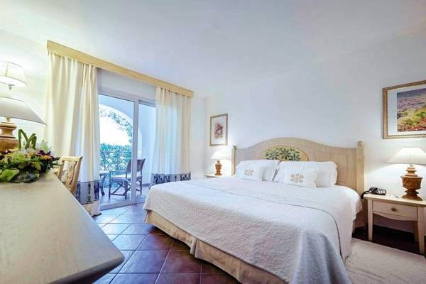 Schlafzimmer im Grand Hotel Poltu Quatu mit großem Bett und Balkonzugang