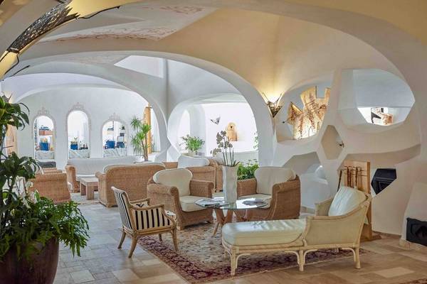 Loungebereich im Grand Hotel Poltu Quatu mit weißen Möbeln und Pflanzen.