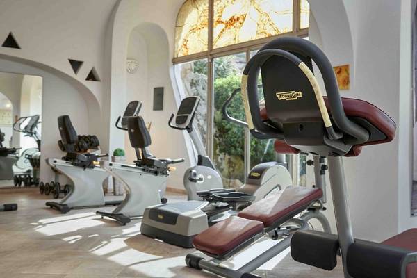 Fitnessstudio im Grand Hotel Poltu Quatu mit Technogym-Geräten und Glasfenstern