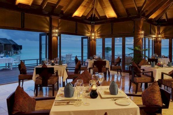 Innenansicht des Restaurants Sun Siyam Olhuveli mit Blick auf das Meer und große Fenster.
