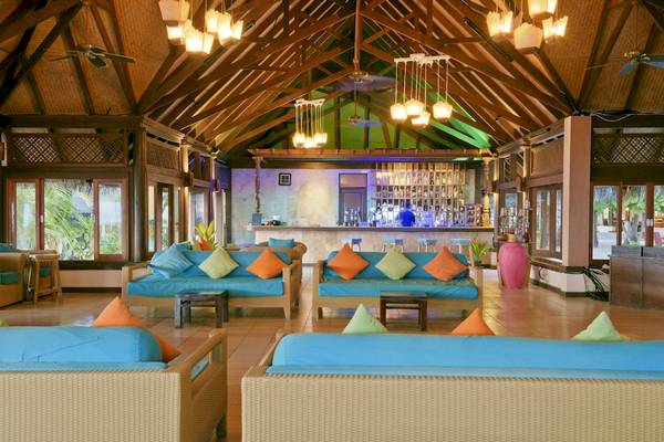 Innenbereich des Sun Siyam Olhuveli Hotels mit Bar, Sofas, Tischen und Dekoration.