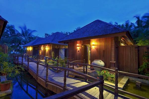 Außenansicht des Sun Siyam Olhuveli Hotels bei Nacht mit beleuchteten Gebäuden und Wassergraben.