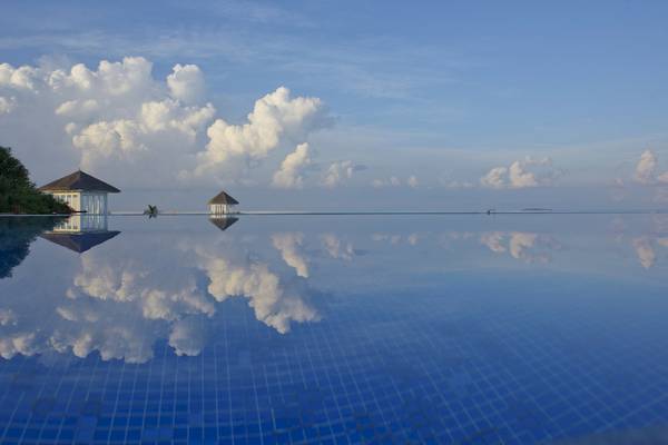 Sonnenaufgang beim Sun Siyam Olhuveli Hotel mit spiegelndem Pool und reflektierten Wolken