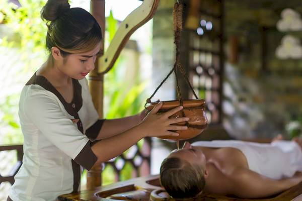 Eine Masseuse gibt einem Gast im Sun Siyam Olhuveli eine Kopfmassage.