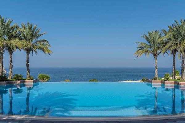 Infinity Pool am Shangri-La Al Husn Resort & Spa mit Blick auf das Meer und Palmen