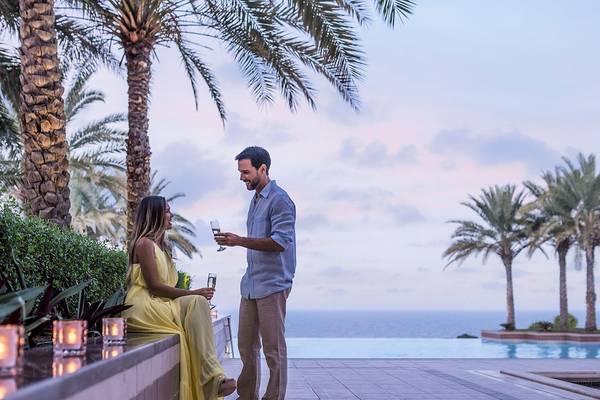 Paar mit Sektgläsern vor dem Pool im Shangri-La Al Husn Resort & Spa