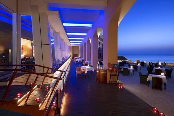 Terrasse des Shangri-La Al Husn Resorts & Spas mit blauen Beleuchtungslichtern, Tischen und Stühlen.