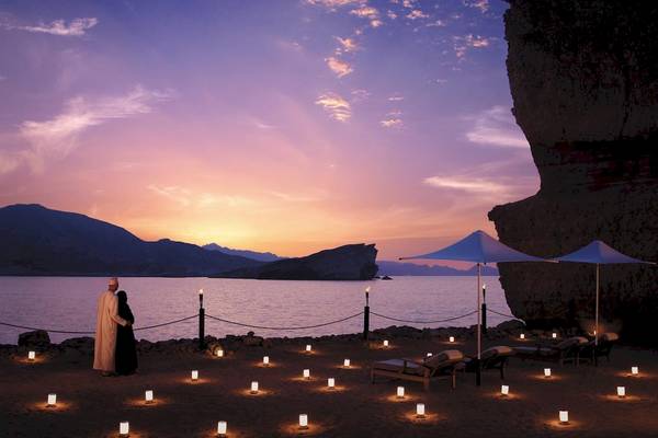 Shangri-La Al Husn Resort & Spa mit romantischem Strand-Setup bei Sonnenuntergang.