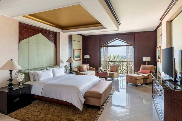 Luxus Schlafzimmer im Shangri-La Al Husn Resort & Spa mit großem Bett, Sitzbereich und Blick auf das Meer.