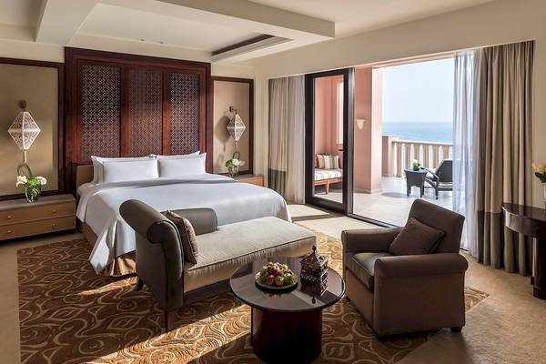 Hotelzimmer im Shangri-La Al Husn Resort & Spa mit Bett, Couch, Tisch und Balkon.
