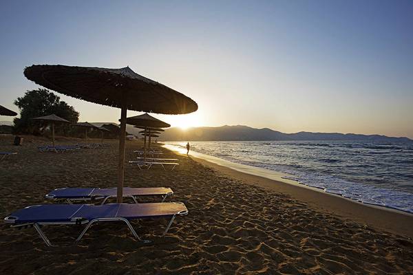 Candia Maris Resort & Spa - Sonnenuntergang am Strand mit Liegen und Sonnenschirmen.