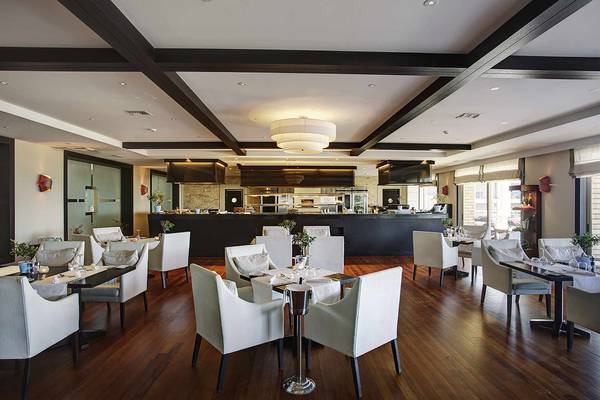 Innenansicht des Restaurants im Candia Maris Resort & Spa mit Holzboden und weißen Möbeln.