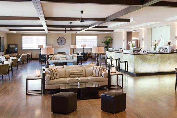Lobby des Candia Maris Resort & Spa mit Sofas, Tischen und einer Bar.