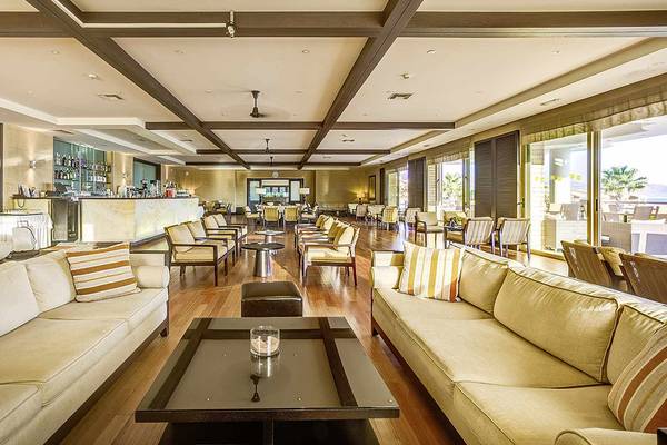 Loungebereich des Candia Maris Resort & Spa mit gepolsterten Sofas, Tischen und einer Bar.