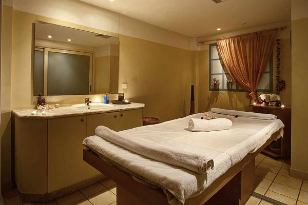 Massageraum im Candia Maris Resort & Spa mit einem Massagetisch, einem Spiegel und einem Waschbecken.