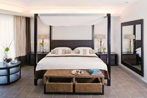 Schlafzimmer im Candia Maris Resort & Spa mit einem Himmelbett, Tisch, Spiegeln und Lampen.